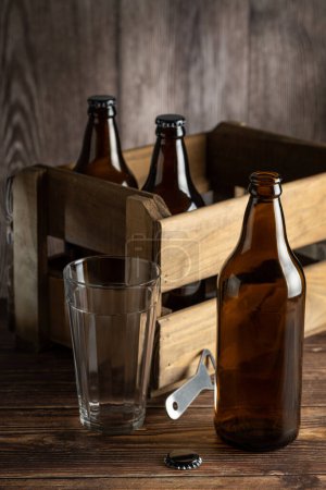 Bouteilles de bière ambre vides sur fond bois rustique.