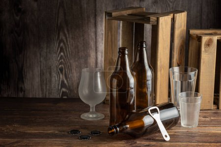 Leere bernsteinfarbene Bierflaschen auf rustikalem Holzgrund.