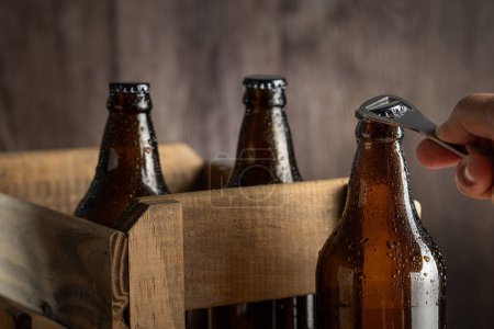 Leere bernsteinfarbene Bierflaschen auf rustikalem Holzgrund.
