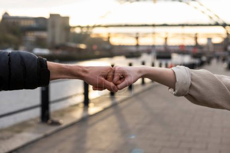 Photo for An unrecognisable couple spending the day in Newcastle Upon Tyne together. They are fist bumping each other while standing near the River Tyne. - Royalty Free Image