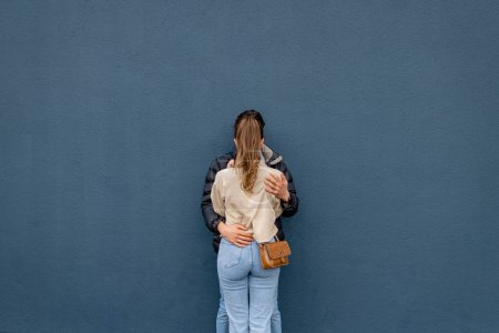 Foto de Una joven pareja pasando el día en Newcastle Upon Tyne juntos. Están de pie contra una pared azul en el centro de la ciudad mientras se besan y se abrazan. - Imagen libre de derechos