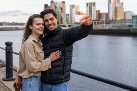 Photo for A wide-view shot of a young couple standing together taking a selfie, they are in love. - Royalty Free Image
