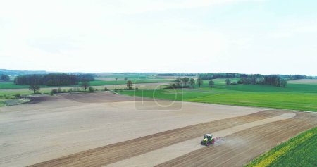 Téléchargez les photos : Prise de vue du tracteur travaillant sur le terrain. L'agriculteur laboure le champ avant de planter du blé. - en image libre de droit