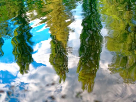 Superficie de agua ondulada con reflejo de árboles. Antecedentes abstractos que recuerdan pinturas impresionistas