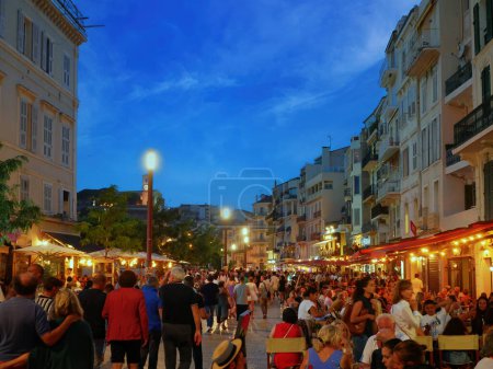 Foto de Cannses, Francia - Junio 2022: Restaurantes callejeros en Cannes Los turistas visitan las tiendas locales al atardecer o por la noche - Imagen libre de derechos