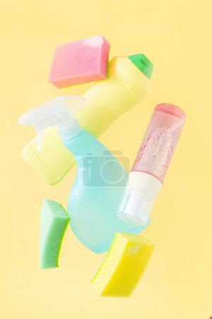 Foto de Cleaning concept - levitation of cleaning supplies on pastel yellow background, copy space - Imagen libre de derechos
