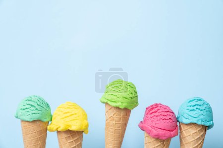 Foto de Colorful ice cream scoops in cones, bright blue background. Top view - Imagen libre de derechos