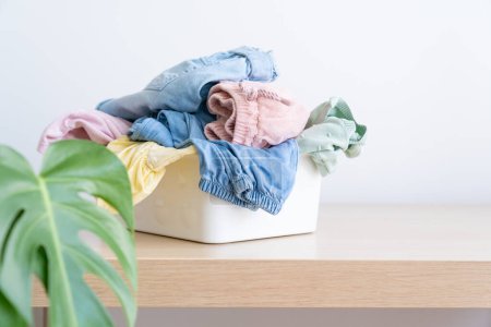 Photo for Selection of fresh unfolded laundry in white basket on wood table. copy space - Royalty Free Image