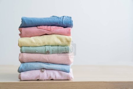 Photo for Stack of clean freshly laundered, neatly folded womens clothes on wooden table. Pile of shirts and sweaters on the table - Royalty Free Image