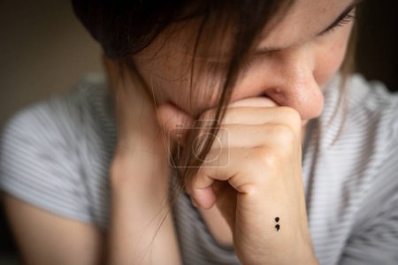 Téléchargez les photos : Concept de dépression - tatouage point-virgule comme symbole de la maladie mentale. Photo de haute qualité - en image libre de droit