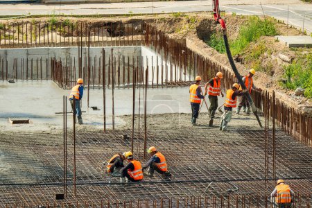 Photo for RUSSIA, KALUGA - AUGUST 15, 2022 : Concrete automatic pump tube working on construction site. Group of workers directing and pouring concrete. - Royalty Free Image