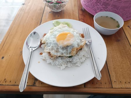 One dish meal was placed on a wooden table, a large fried egg.