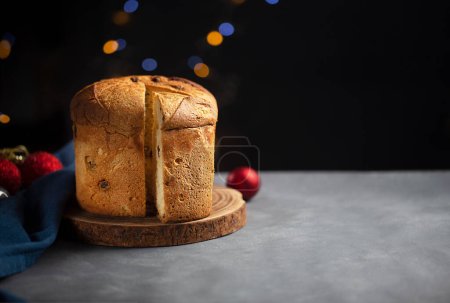 Foto de Un pedazo de pan dulce panettone, comida italiana tradicional para Navidad sobre un fondo oscuro con espacio para copiar y decoraciones navideñas - Imagen libre de derechos