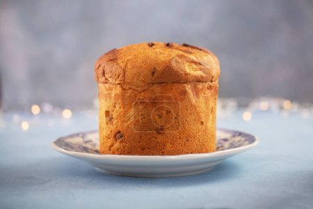 Foto de Un panettone pan dulce, comida tradicional italiana para Navidad con guirnalda de iluminación sobre un fondo - Imagen libre de derechos