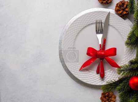 Foto de Ajuste de mesa de Navidad que consta de un plato blanco y cubiertos atados con un lazo. Vista superior, sobre fondo blanco con espacio para copiar - Imagen libre de derechos