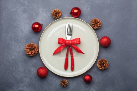 Foto de Ajuste de mesa de Navidad que consta de un plato y cubiertos atados con un lazo. Puesta plana, sobre fondo azul - Imagen libre de derechos