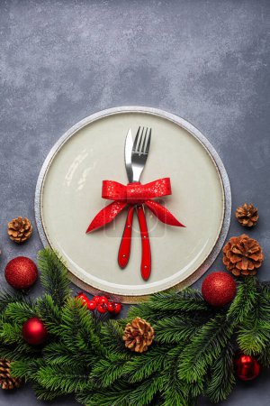 Foto de Ajuste de mesa de Navidad que consta de un plato y cubiertos atados con un lazo. Vista superior, sobre fondo azul - Imagen libre de derechos