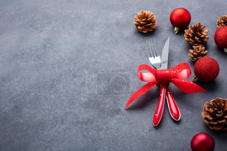 Foto de Ajuste de mesa de Navidad que consta de cubiertos, cuchillo y tenedor atados con un lazo rojo con decoraciones de Navidad en una mesa - Imagen libre de derechos