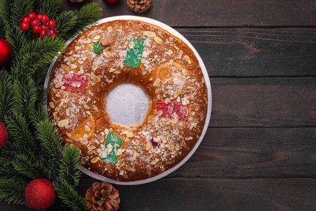 Téléchargez les photos : Roscon est une pâtisserie de Noël espagnole traditionnelle faite avec de la pâte, de la crème au beurre douce et des fruits confits. Ce plat est servi à la table de fête en Espagne et en Amérique latine. Vue d'en haut sur le noir - en image libre de droit