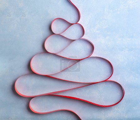 Téléchargez les photos : Arbre de Noël créatif en ruban rouge sur fond bleu. Vue du dessus - en image libre de droit