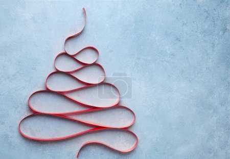 Téléchargez les photos : Arbre de Noël créatif en ruban rouge sur fond bleu. Vue supérieure avec espace de copie - en image libre de droit