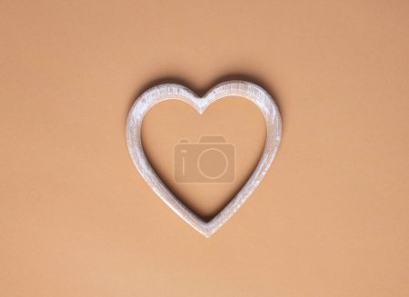 Téléchargez les photos : Wooden heart on a beige background. Simple concept for Valentines day holiday. High quality photo - en image libre de droit