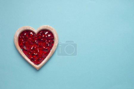 Téléchargez les photos : Wooden heart and red glass hearts on a blue background with copy space. Simple concept for Valentines day holiday. High quality photo - en image libre de droit