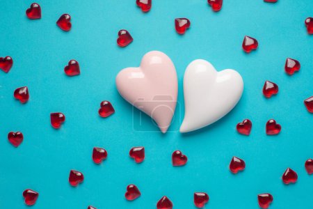 Téléchargez les photos : Two white and lot of red hearts on a blue background. Simple concept for Valentines day holiday. High quality photo - en image libre de droit