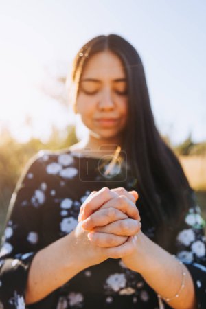 Téléchargez les photos : Young woman with praying hands at sunset in the field. Submission to God. High quality photo - en image libre de droit