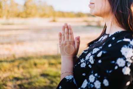Téléchargez les photos : Unrecognizable young woman with praying hands at sunset in the field. Submission to God. High quality photo - en image libre de droit
