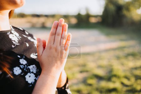 Téléchargez les photos : Unrecognizable young woman with praying hands at sunset in the field. Submission to God. High quality photo - en image libre de droit