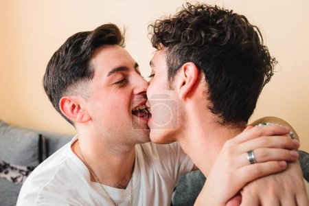 Téléchargez les photos : Deux hommes gays portant des t-shirts blancs, s'embrassant sur la bouche. Relation LGBT. Photo de haute qualité - en image libre de droit
