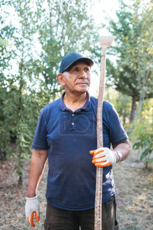Photo for Headshot portrait of a senior indigenous hispanic farmer man holding a garden scraper in countryside. High quality photo - Royalty Free Image