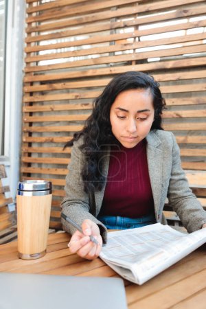 Photo for Job Hunting in Style: Young Latina Woman Searching for Employment Opportunities in a Cozy Cafe. High quality photo - Royalty Free Image