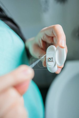 Photo for Hands of Unrecognizable Girl Doing Oral Hygiene Routine by Using Dental Floss to Clean Her Teeth in the Bathroom. High quality photo - Royalty Free Image