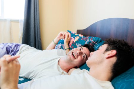 Photo for Close up shot of loving same sex male couple lying on bed at home hugging together. High quality photo - Royalty Free Image