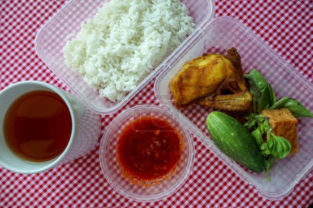 Traditionelle indonesische Mahlzeit mit gebratenem Huhn, Tofu, Tempeh, frischem Gemüse, weißem Reis, Sambal Pecel und ungesüßtem Tee