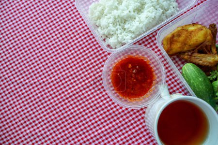 Traditionelle indonesische Mahlzeit mit gebratenem Huhn, Tofu, Tempeh, frischem Gemüse, weißem Reis, Sambal Pecel und ungesüßtem Tee