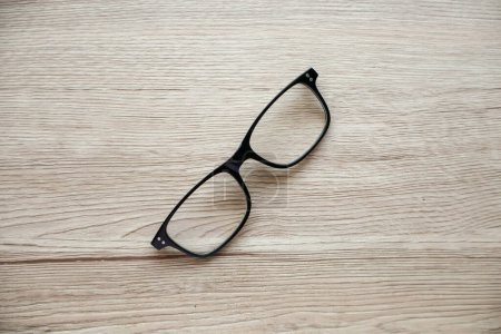Un par de gafas de lectura rotas sin varillas, colocadas sobre una mesa. El daño a las gafas es evidente, mostrando el desgaste del uso diario