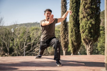 A man immerses himself in the practice of Kung Fu, a Chinese martial art, in the stance within the form of Xiao Ba Ji Quan in a natural setting. Connection between mind, body, and environment.