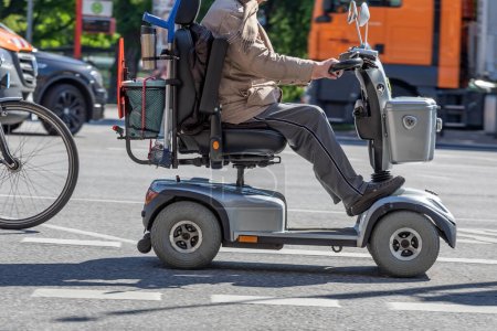 Photo for Elderly man on electric wheelchair rides on the street - Royalty Free Image
