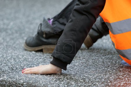 Téléchargez les photos : A climate activist glued herself to the asphalt with superglue - en image libre de droit