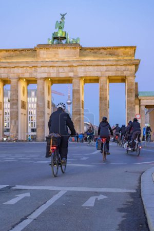 Téléchargez les photos : Cyclistes au crépuscule à la porte de brandenburg - en image libre de droit