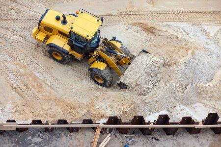 Wheel loader excavating an excavation pit with a sheet pile wall