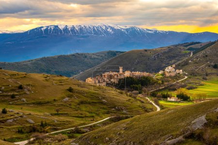 Téléchargez les photos : Vue sur le village Santo Stefano di Sessanio dans les Abruzzes dans le parc national du Gran Sasso et les monts Majella avec ses collines et ses hautes chaînes au coucher du soleil romantique - en image libre de droit