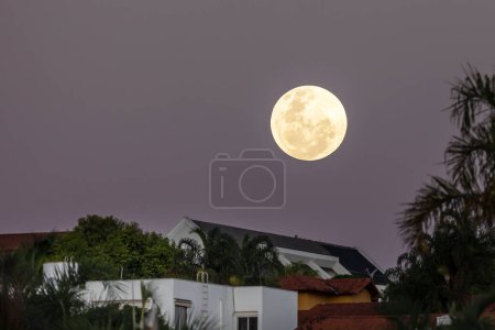 Téléchargez les photos : La pleine lune sous les maisons dans une rue. Astronomie. Nature. - en image libre de droit