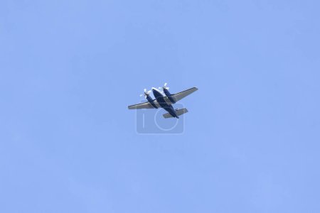 Photo for Silhouette of a twin-engine plane flying in a blue sky between clouds. Transportation. Aircraft. - Royalty Free Image