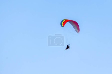 Photo for A Powered paragliding also knows as Paramotor flying through the blue sky. Sport. Leisure. Adventure. - Royalty Free Image