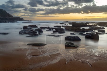 Téléchargez les photos : Longue exposition à l'océan avec de l'eau laiteuse et des roches au lever du soleil à Spoon Bay - en image libre de droit