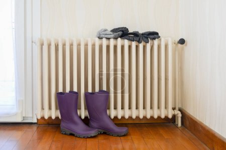 Photo for Boots, hat and gloves drying on a cast-iron radiator - Royalty Free Image